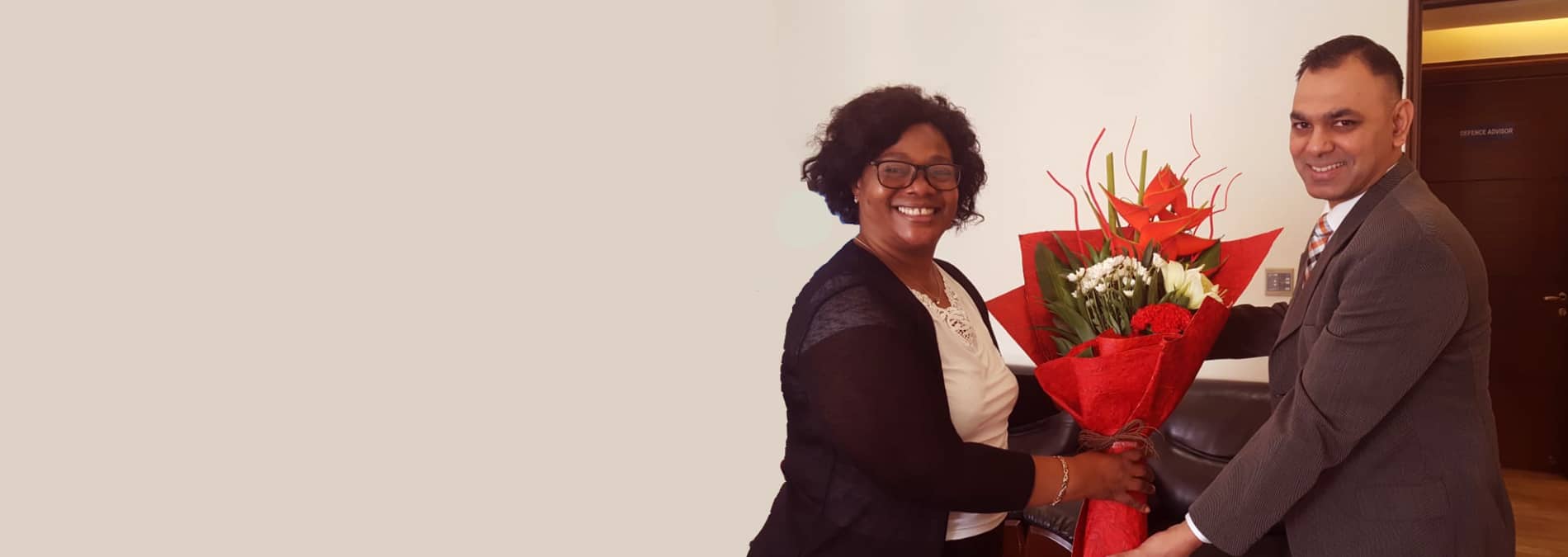 Amit Suden presenting a bouquet at a formal meeting