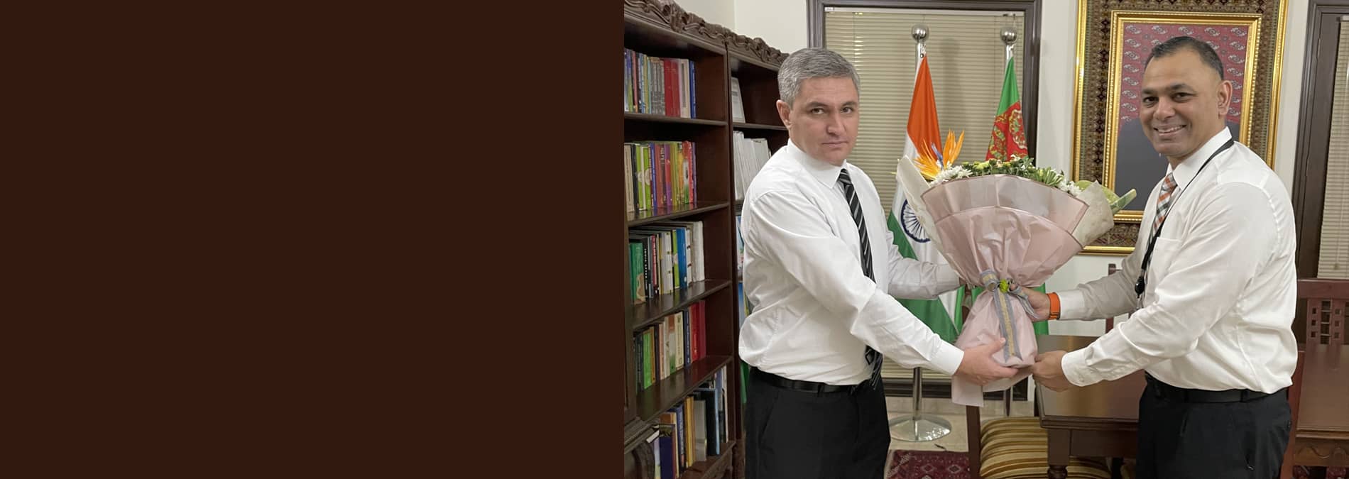 Amit Suden exchanging a bouquet with a guest in an office